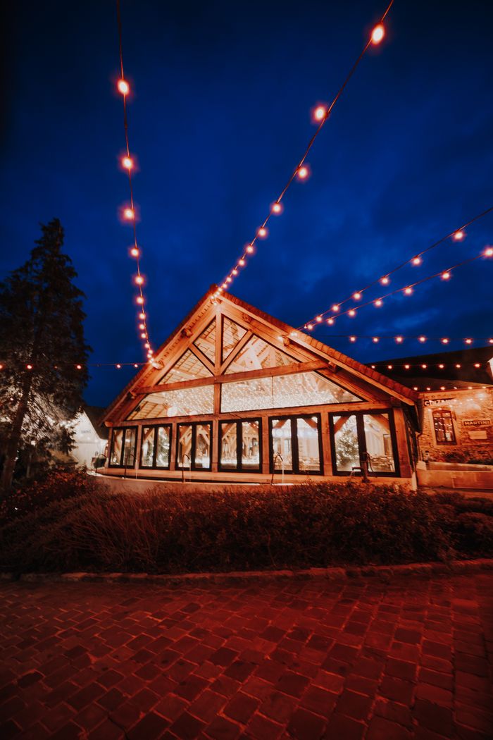 Warmly lit cabin with festive string lights under a deep blue night sky.